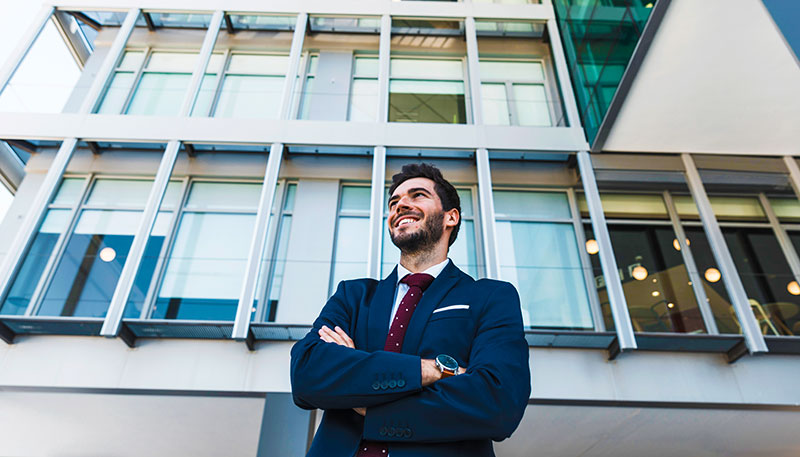 LinkedIn Sales Navigator 10 commercial real estate broker smiling in front of big apartment complex.